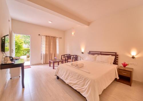 a bedroom with a bed and a table and a desk at Ministers Mansion Kanthalloor Pool Resort by VOYE HOMES in Kanthalloor