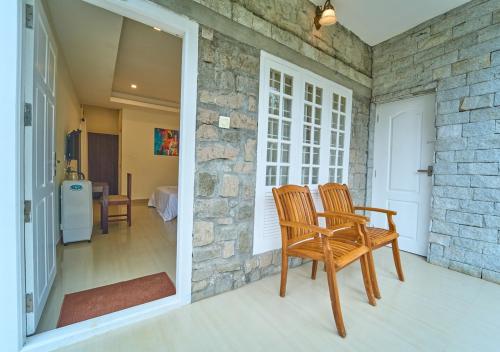 a room with two chairs and a stone wall at Ministers Mansion Kanthalloor Pool Resort by VOYE HOMES in Kanthalloor