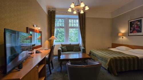 a hotel room with a bed and a desk with a television at Barclay Hotel in Tartu
