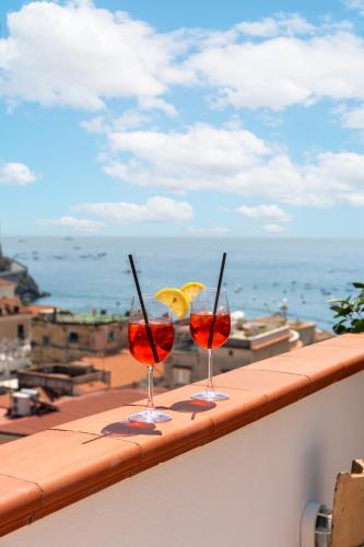 two wine glasses sitting on a ledge with a view of the ocean at Torre Paradiso in Minori