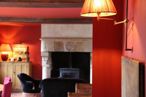 sala de estar con paredes rojas y chimenea en Auberge Bout de Bois, en Saint-Jouin-Bruneval