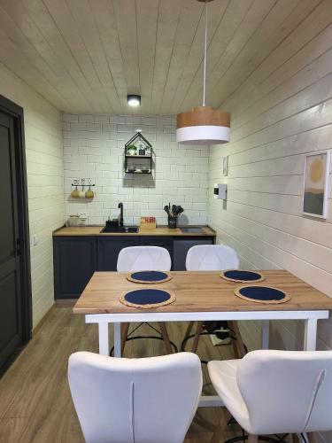 a kitchen with a wooden table and white chairs at White Scandinavian Barn House in Artavaz