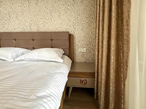 a bed with white pillows and a curtain next to at Stylish Apartment in Prestigious Towers in Baku in Baku