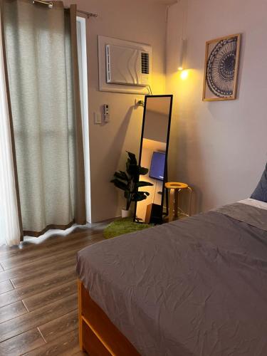 a bedroom with a bed and a mirror and a plant at Layover Stays 3 mins to Cebu Mactan Airport with Pool and Gym in Pusok