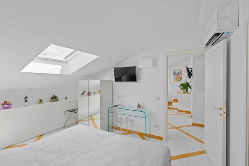 a white bedroom with a bed and a tv at Torre Paradiso in Minori