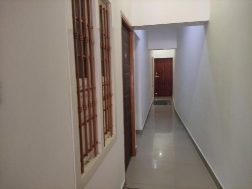 a hallway with white walls and wooden doors at Temple opposite Rooms in Tiruvannāmalai