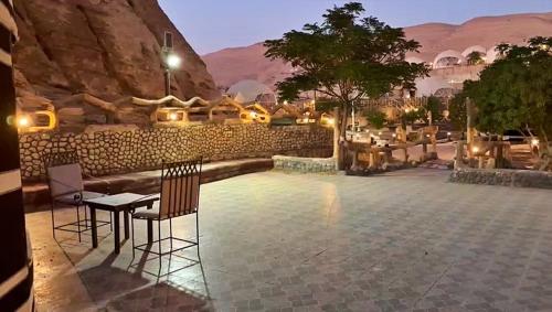 un patio con tavolo e sedie e un muro di pietra di Seven Wonders Luxury Camp a Wadi Musa