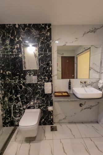 a bathroom with a toilet and a sink and a mirror at Seven Sky Clarks Exotica in Bhuj