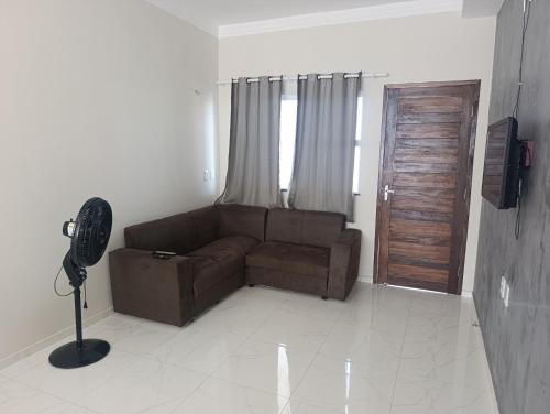 a living room with a brown couch and a door at Sua casa pertinho da praia in Camocim
