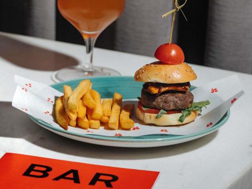 a hamburger and french fries on a plate with a drink at Manto Hotel Lima - MGallery Collection in Lima