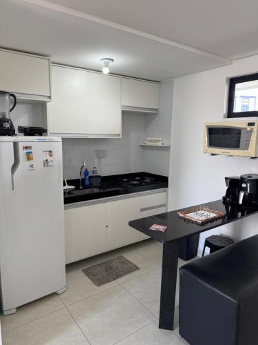 Una cocina con un refrigerador blanco y una mesa. en FLAT ALTO PADRÃO NO CENTRo, en Campina Grande