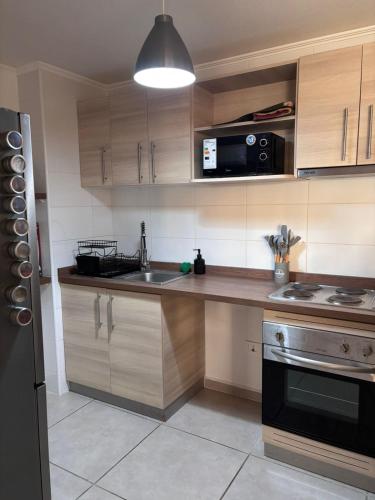 a kitchen with wooden cabinets and a sink and a microwave at Dpto Vista al Mar, La Herradura in Coquimbo