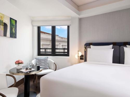a bedroom with a white bed and a table and chairs at Athens Capital Center Hotel - MGallery Collection in Athens