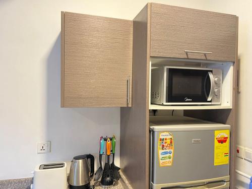 a kitchen with a microwave on top of a refrigerator at Accra City Studios & Apartment in Accra