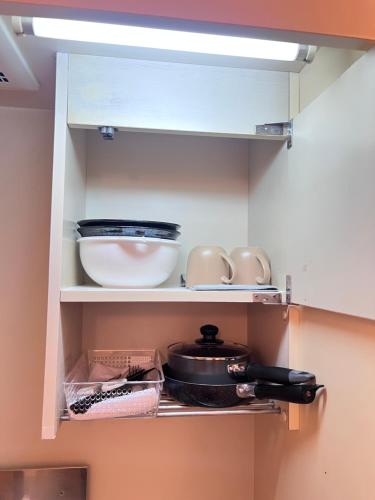 a kitchen shelf with dishes and a pot and pans at Nishi Kawaguchi Buryry in Kawaguchi