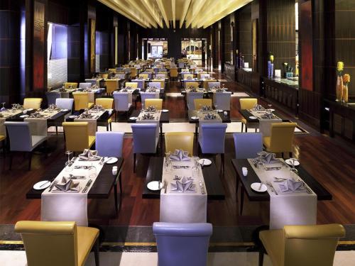 a row of tables and chairs in a restaurant at La Cigale Hotel Managed by Accor in Doha