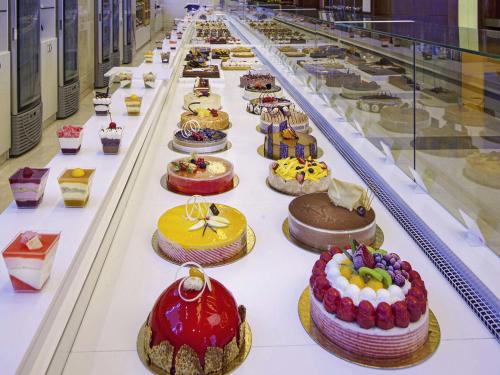 a long table filled with lots of cakes at La Cigale Hotel Managed by Accor in Doha