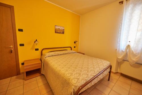 a yellow bedroom with a bed and a window at Agriturismo La Panoramica in Assisi