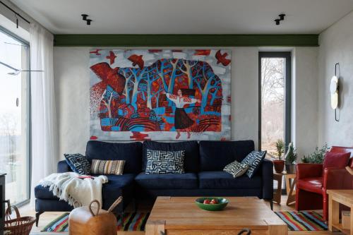 a living room with a blue couch and a painting at Two Doves House in Pohrebea