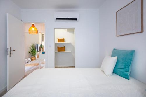 a white bedroom with a white bed and a blue pillow at Micului Refugiu in Albufeira