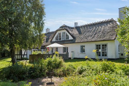 a white house with an umbrella in a yard at Idyllic Half-Timbered House For 10 Guests in Kettinge