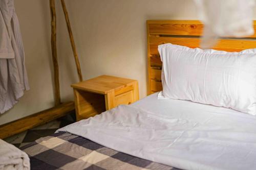 a bedroom with a white bed with a wooden headboard at Vintage Room - Nostalgic charm for couples in Gulu