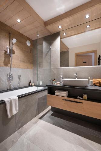 a bathroom with a tub and a sink and a shower at MGM Hôtels & Résidences - Résidence Le Hameau de l'Ours in Manigod