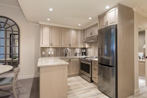 a kitchen with a stainless steel refrigerator and cabinets at Woodrun Lodge 616 | Stylish Top Floor Ski-In & Out Condo by Upper Village w/ Hot Tub, Pool, Parking in Whistler