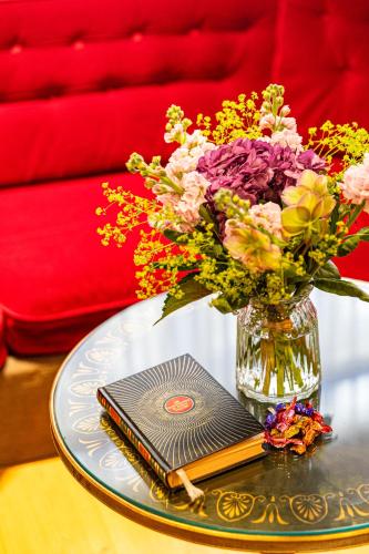 a vase of flowers and a book on a table at Hotel Claude Bernard Saint-Germain in Paris