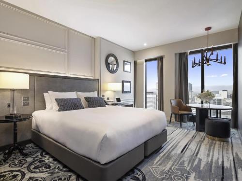 a bedroom with a large bed and a dining room at Sofitel Adelaide in Adelaide