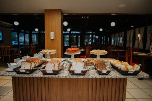 a buffet line with different types of cakes and pastries at Hotel Raul's in Gaspar