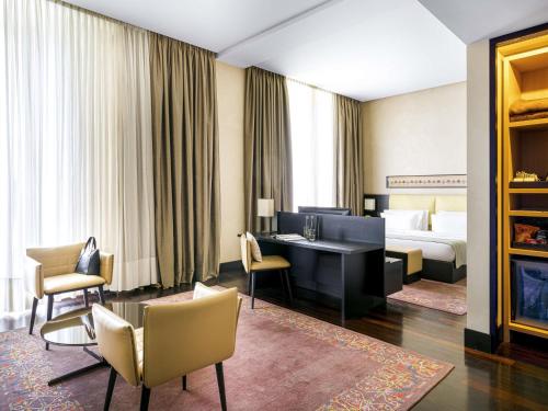 ein Hotelzimmer mit einem Bett, einem Schreibtisch und Stühlen in der Unterkunft BERDS Hotel Chisinau - MGallery Collection in Chişinău
