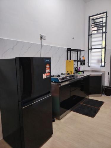a kitchen with a black refrigerator and a counter at FH Homestay Kuala Lipis 3R2B in Kuala Lipis