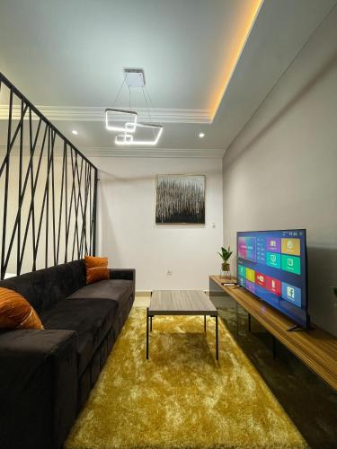 a living room with a couch and a flat screen tv at Teak Gardens T1 - East Legon in Accra