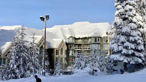 a snow covered building with a snow covered roof at Woodrun Lodge 306 | Budget-friendly Ski-in-Ski-out Condo w/ Heated Pool, Hot Tub, Fireplace in Whistler