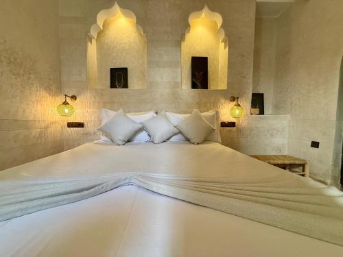 a large white bed in a room with two mirrors at Riad Jolie in Marrakesh