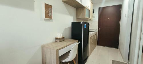 een kleine keuken met een zwarte koelkast en een tafel bij Novara Living Springwood Residences in Warungmangga