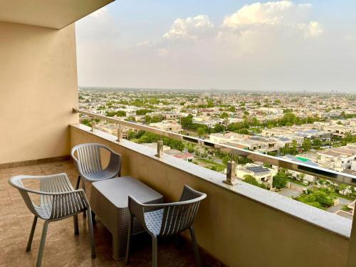 a balcony with chairs and a view of a city at Luxurious One-Bedroom Gold Crest Apartment with Stunning Balcony Retreat DHA Lahore in Lahore