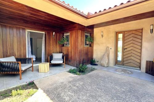 une terrasse couverte d'une maison avec un mur en bois dans l'établissement Villa Taglio Rosso Di Santa Lucia, à Sainte-Lucie de Porto-Vecchio