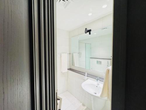 a white bathroom with a sink and a mirror at Taj Hotel Premium Residency F-7 Islamabad in Islamabad