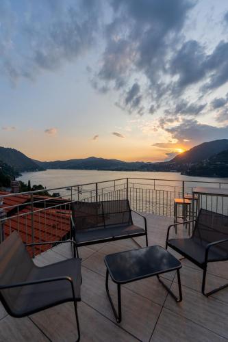 a group of chairs and tables on a deck with a sunset at DN ART ROYALE - APT N vasca idromassaggio interno piano terra -APT D esclusivo terrazzo esterno con jacuzzi in Blevio