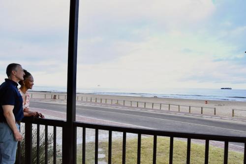a man and woman standing on a balcony looking at the beach at 3-bedroom beach house in Langstrand