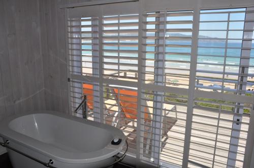 布菲尔斯巴埃Main beachfront house Halleluja II, Buffalo Bay的带浴缸的浴室以及享有海滩景致的窗户。