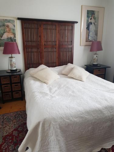 a bedroom with a large white bed with two lamps at Studiolägenhet i villa in Huddinge