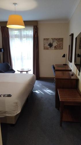 a hotel room with a bed and a desk and a window at London Thames Lodge by Dancenter in Staines