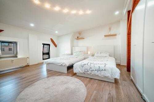two beds in a large room with wood floors at Charming old building for 2 in Magdeburg