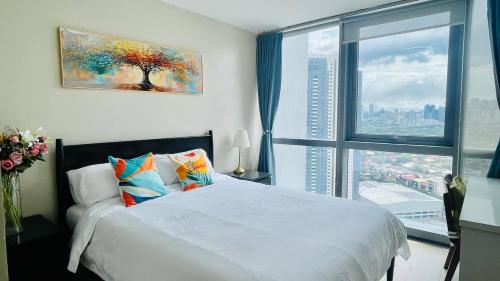 une chambre avec un lit blanc et une grande fenêtre dans l'établissement 2 bedroom Luxury Condo in Eastwood with Scenic City view, unli wifi and netflix, à Manille