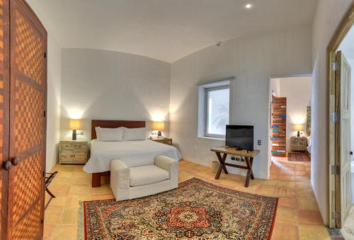 a bedroom with a bed and a chair and a television at Hotel Boutique Casareyna in Puebla