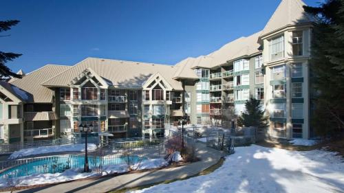 a large apartment building with snow on the ground at Woodrun Lodge 517 | Large Ski-In Ski-Out Condo by Upper Village w/ Mountain Views & Shared Hot Tub in Whistler