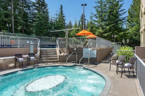 a swimming pool with chairs and an umbrella at Woodrun Lodge 517 | Large Ski-In Ski-Out Condo by Upper Village w/ Mountain Views & Shared Hot Tub in Whistler